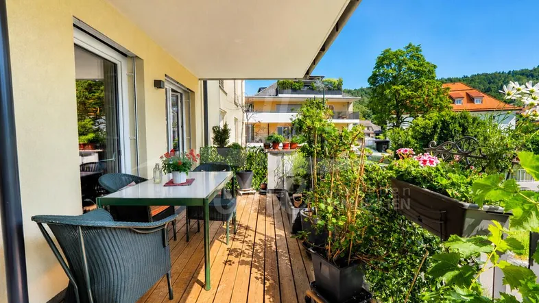 Geräumiger Balkon mit Holzboden, Sitzgelegenheiten und vielen Pflanzen, bietet einen angenehmen Außenbereich.
