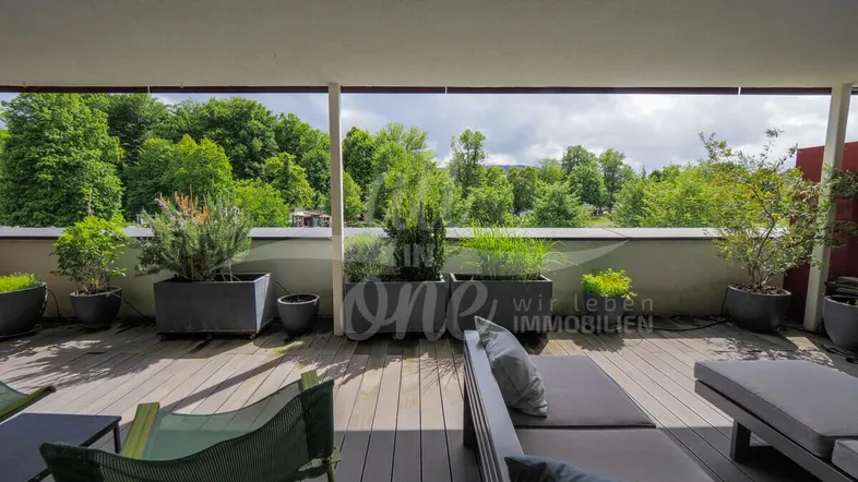 Geräumige Terrasse mit bequemen Lounge-Möbeln, Pflanzen und weitem Blick ins Grüne.