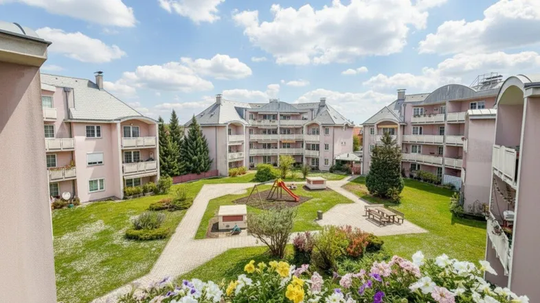 Blick von einem Balkon auf den grünen Innenhof mit Spielplatz und Wohngebäuden.