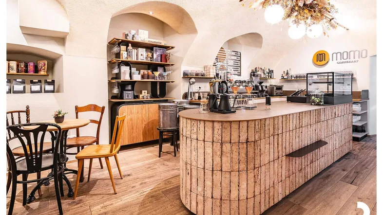 Heller Innenraum eines Cafés mit Theke, Holzboden und gewölbten Decken, einladende Atmosphäre.