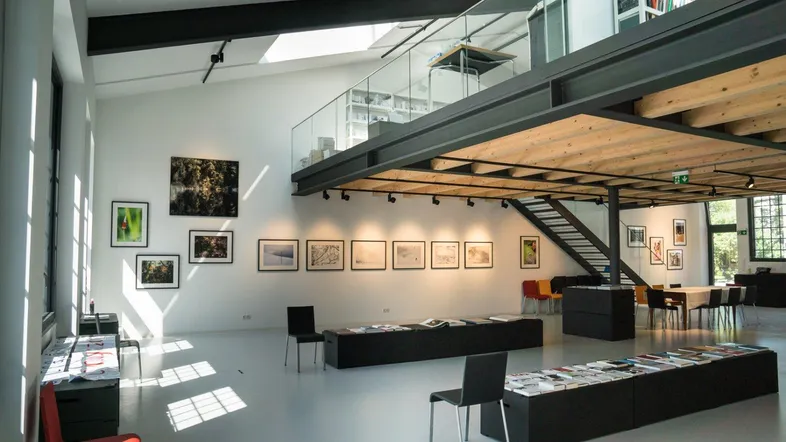 Geräumiger Loftbereich mit hohen Decken, großen Fenstern, einer Galerie und moderner Einrichtung.
