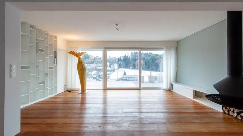 Helles Wohnzimmer mit Holzboden, modernem Hängekamin und großen Fenstern mit Weitblick.