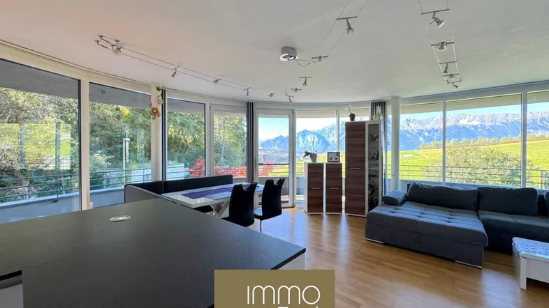 Heller offener Wohn- und Essbereich mit integrierter Küche, Panoramablick auf die Berge und Holzboden.
