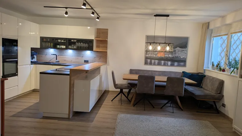 Moderne offene Wohnküche mit Kochinsel, Essbereich und hellem Laminatboden.