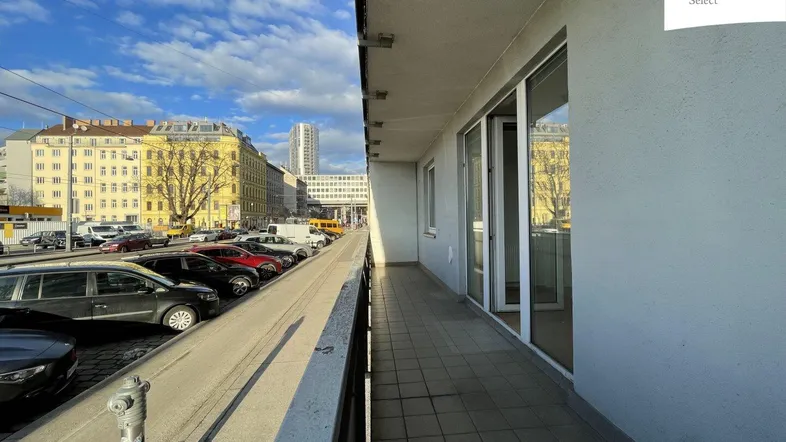 Langer Balkon mit Blick auf die Straße und die umliegenden Gebäude an einem sonnigen Tag.