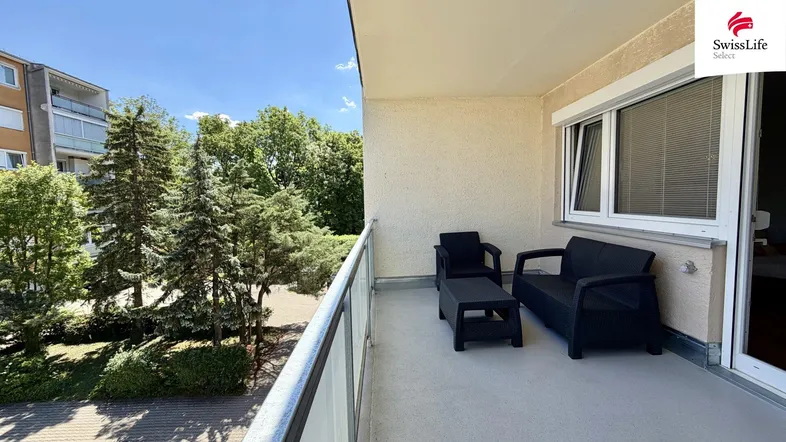 Geräumiger Balkon mit Sitzmöbeln und Blick auf Bäume und die Umgebung.