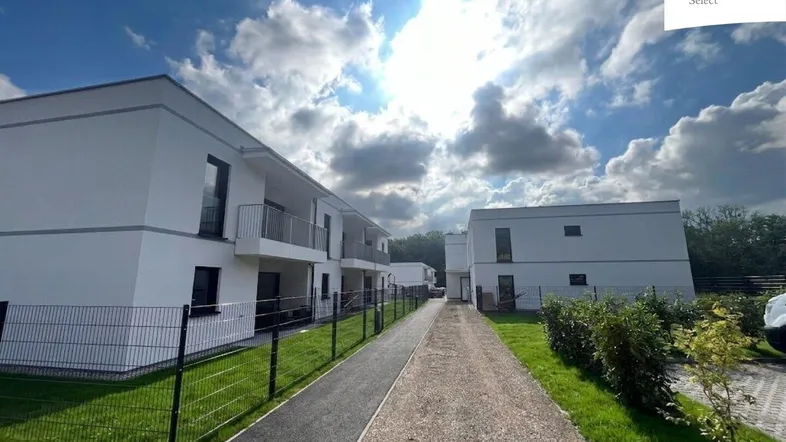 Moderne Wohngebäude mit weißer Fassade und Balkonen unter blauem Himmel.