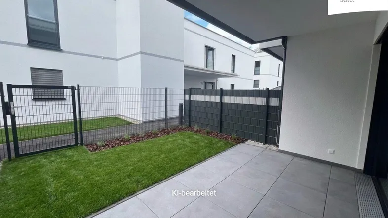 Moderne Terrasse mit Fliesenboden und kleinem Rasenbereich, umgeben von einem Zaun.