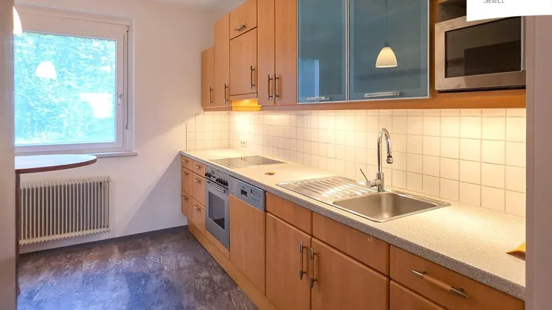 Funktionale Küche mit Holzschränken, Fliesenrückwand und Fenster mit Blick ins Grüne.