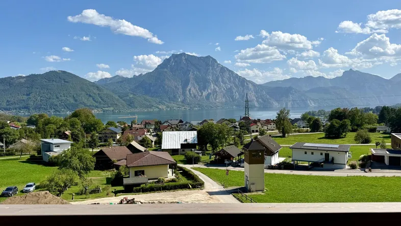Spektakulärer Blick von einem Balkon auf einen See, Berge und ein malerisches Dorf.