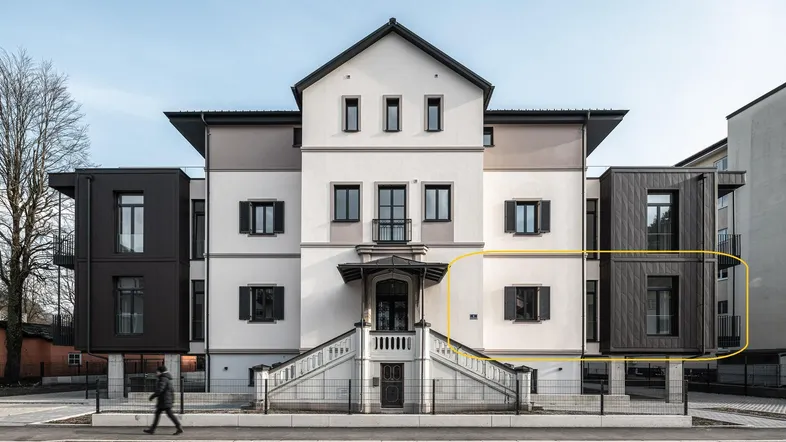 Ansicht der modernen Wohnanlage mit traditionellen Elementen und dunklen Anbauten.