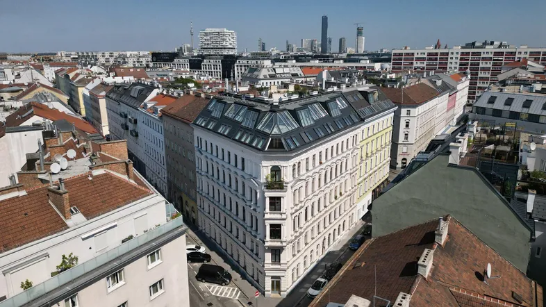 Luftaufnahme eines Eckgebäudes in einem städtischen Viertel mit Blick auf die Skyline.