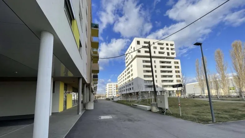 Moderne Wohngebäude mit farbigen Balkonen und einer Zufahrtsstraße unter blauem Himmel.