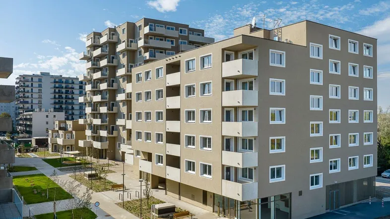 Moderne Wohngebäude mit zahlreichen Balkonen, umgeben von gepflegten Grünflächen und Gehwegen.