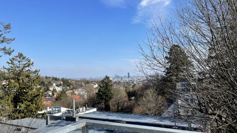 Blick von der Terrasse auf die Stadt und die umliegende Landschaft unter blauem Himmel.