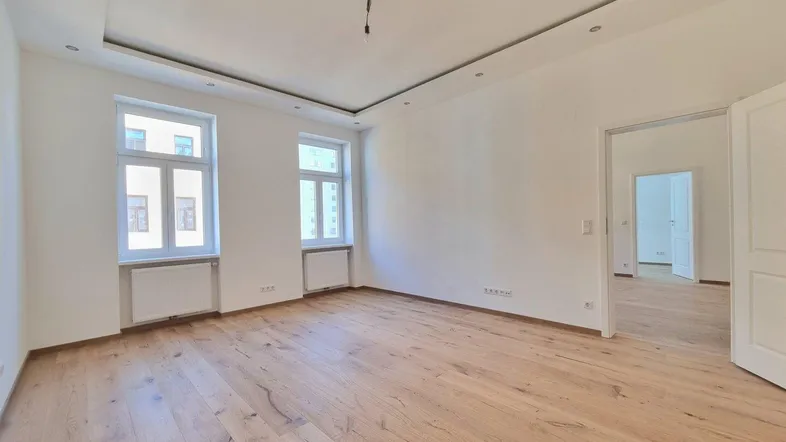 Helles, leeres Zimmer mit neuem Parkettboden und zwei Fenstern, bereit zur individuellen Gestaltung.