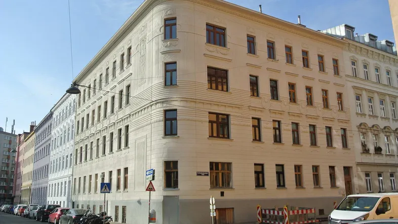 Historisches Eckgebäude mit klassischer Fassade und vielen Fenstern an einer städtischen Straße.