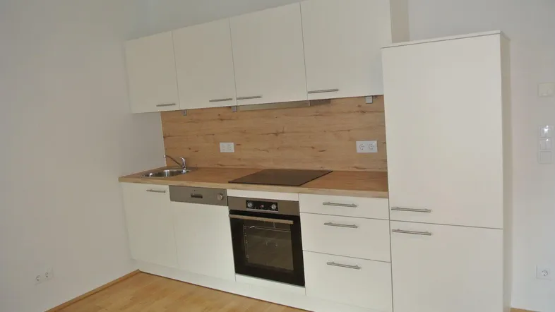Moderne Einbauküche mit weißen Fronten, Holzoptik-Arbeitsplatte und integrierten Geräten.