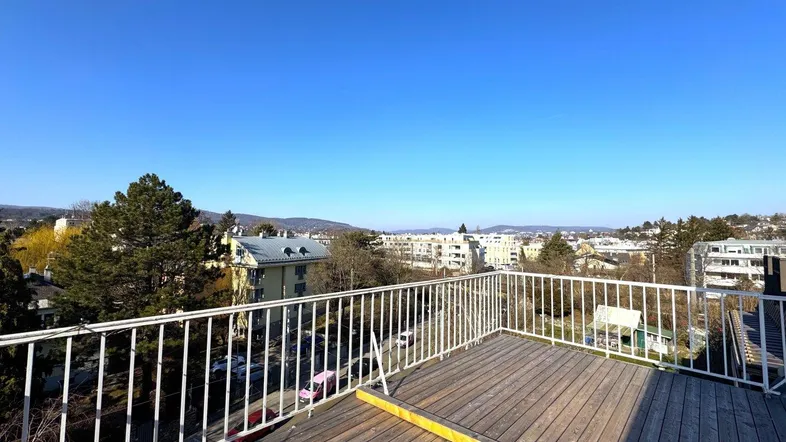 Geräumige Dachterrasse mit Holzboden und weitem Blick über die Stadt und die umliegende Landschaft.