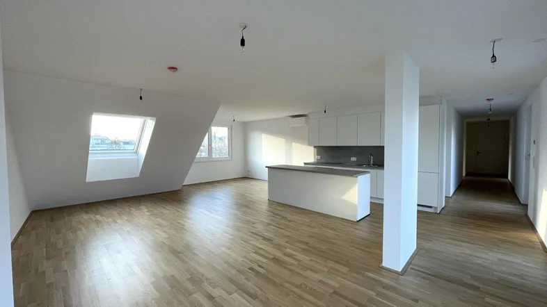 Heller, offener Wohnbereich mit moderner Einbauküche, Holzboden und Dachfenstern, ideal für modernes Wohnen.
