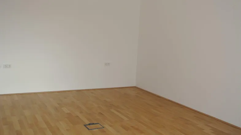 Leerer Raum mit hellen Wänden und Holzboden, bereit für die individuelle Gestaltung.