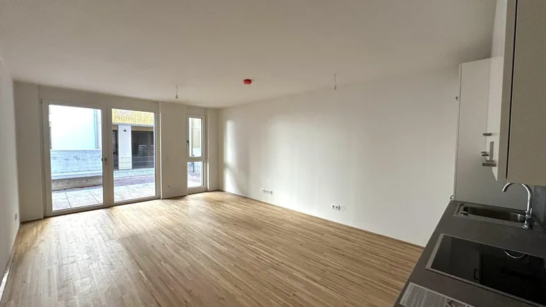 Heller Wohn- und Essbereich mit Parkettboden und Zugang zu einer Terrasse.