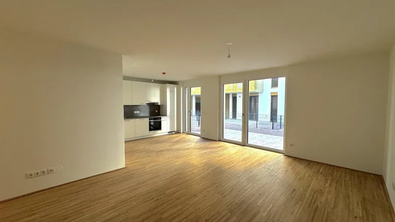 Helles, offenes Wohnzimmer mit integrierter Küche und Zugang zur Terrasse.