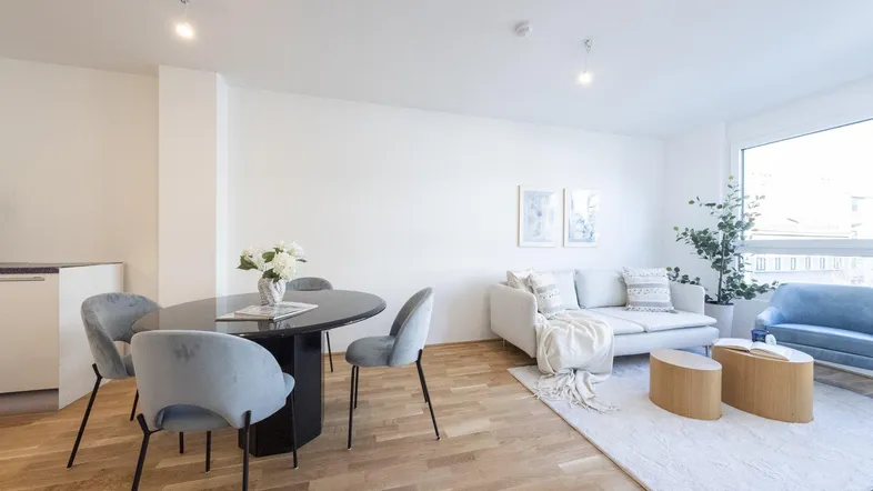 Helles Wohn- und Esszimmer mit modernem Esstisch, bequemen Sofas und Holzboden.