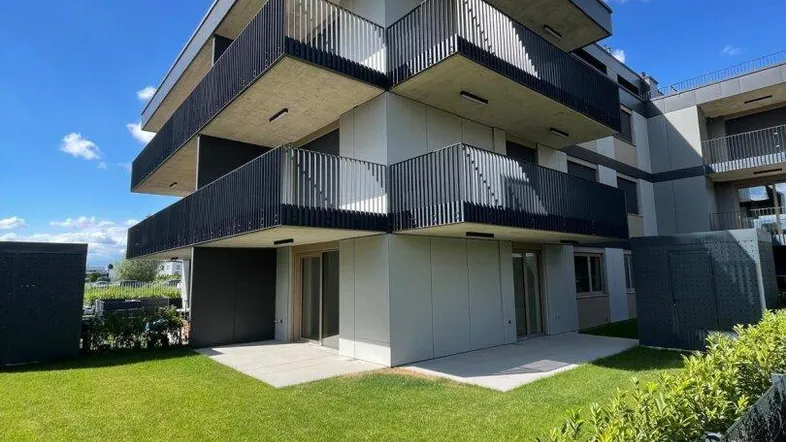 Modernes Mehrfamilienhaus mit mehreren Balkonen und einer gepflegten Rasenfläche im Vordergrund.