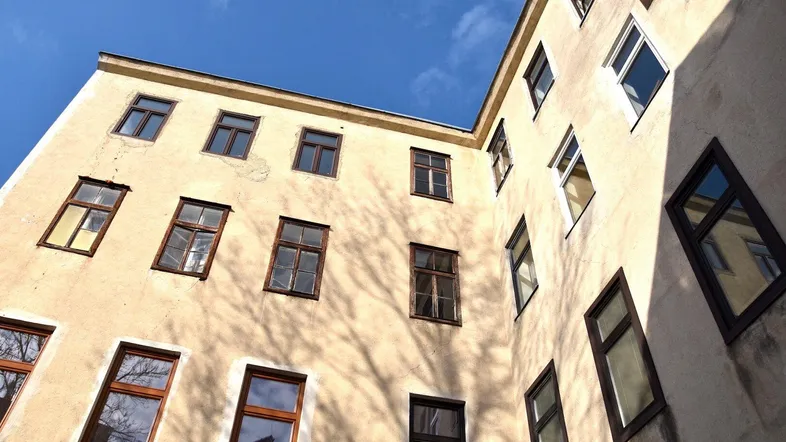 Blick auf die Fassade eines Altbaus mit vielen Fenstern und Schattenwurf im Innenhof.