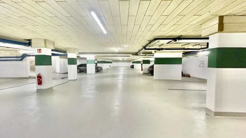 Geräumige Tiefgarage mit markierten Stellplätzen und einigen geparkten Fahrzeugen.