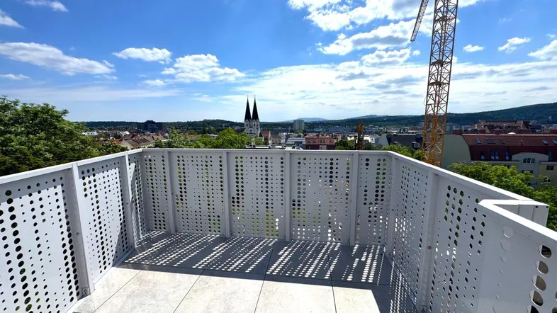 Große Dachterrasse mit modernem Geländer, Fliesenboden und weitem Blick über die Stadt.