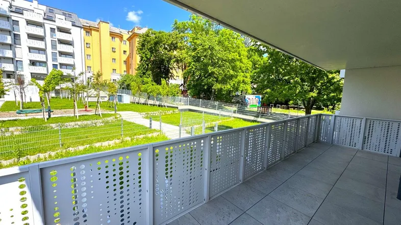 Geräumiger Balkon mit Blick auf den begrünten Innenhof und umliegende Wohngebäude.