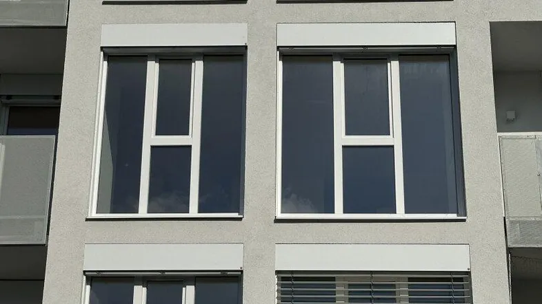 Moderne Fassade eines Wohngebäudes mit zahlreichen Fenstern und Rollläden.