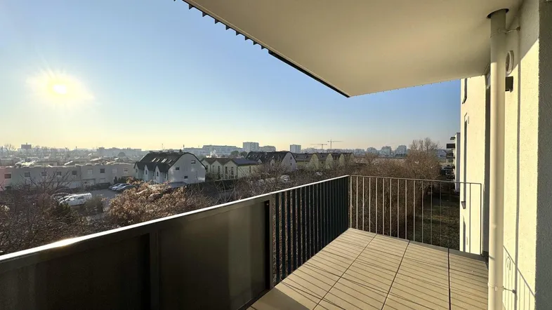 Heller Balkon mit Fliesenboden und weitem Blick über die Stadtlandschaft bei Sonnenschein.