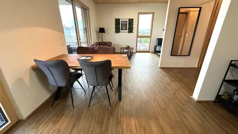 Heller offener Wohn- und Essbereich mit Holzboden, modernen Möbeln und Zugang zur Terrasse.
