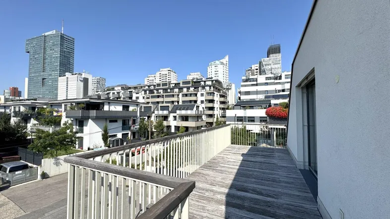 Große Holzterrasse mit modernem Geländer und weitem Blick auf die Stadtlandschaft.