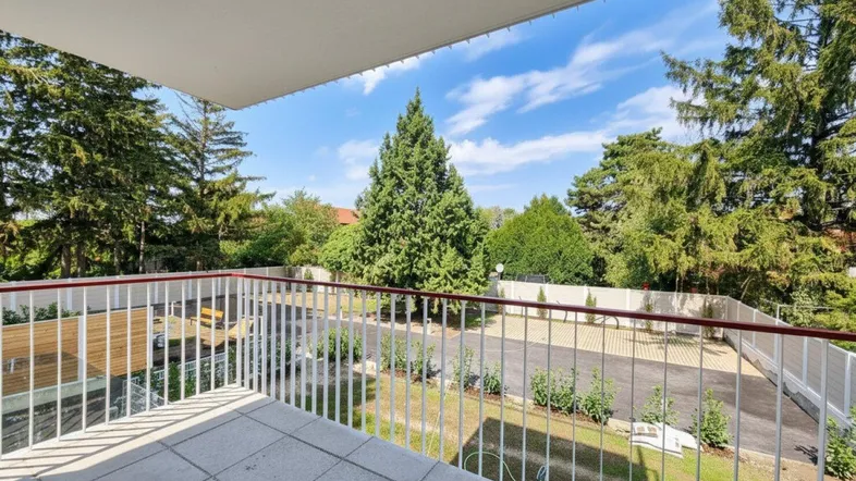 Geräumiger Balkon mit Fliesenboden und weitem Blick ins Grüne, umgeben von Bäumen.