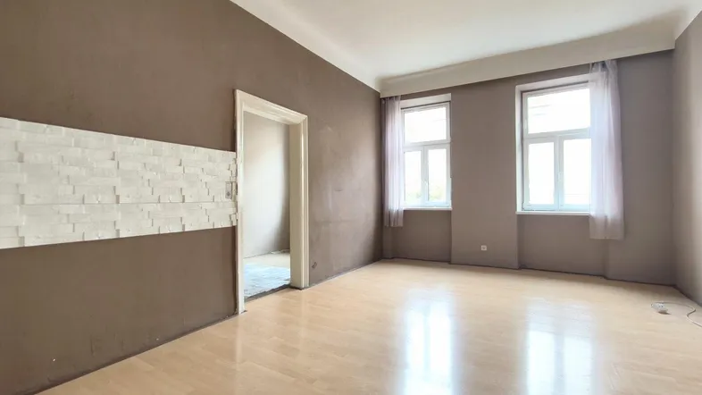 Helles, leeres Zimmer mit Parkettboden und zwei Fenstern, bereit zur individuellen Gestaltung.
