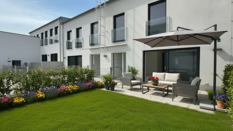 Moderner Gartenbereich mit Rasenfläche, Blumenbeeten und einer möblierten Terrasse am Neubau.