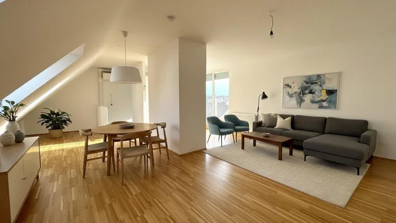 Helles, offenes Wohn- und Esszimmer mit Holzboden, Dachschrägen und moderner Einrichtung.