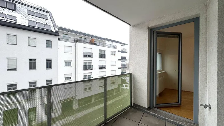 Geräumiger Balkon mit Fliesenboden und Blick auf die umliegenden Wohngebäude in der Stadt.