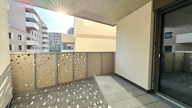 Heller Balkon mit modernen Lochblech-Geländern und Blick auf die umliegenden Gebäude.