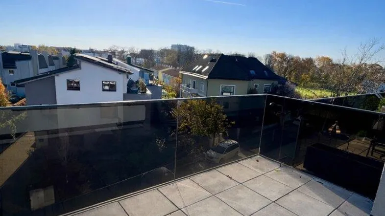 Große, sonnige Dachterrasse mit modernen Fliesen und Glasgeländer, bietet weite Aussicht.