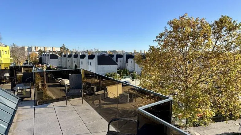 Große Dachterrasse mit modernen Glasgeländern und Blick auf die umliegende Wohnbebauung.