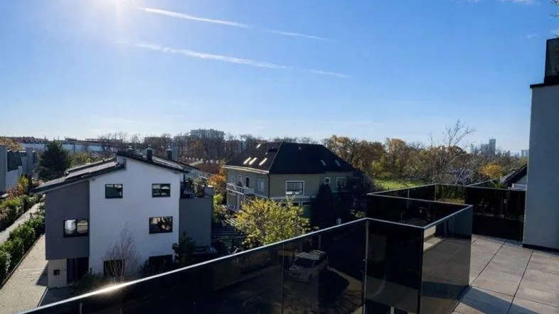 Große Dachterrasse mit modernen Fliesen und Glasgeländer, bietet einen weiten Blick über die Umgebung.