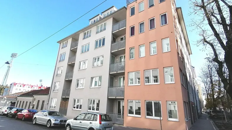 Modernes Mehrfamilienhaus mit hellen Fassaden und Balkonen an einer städtischen Straße.