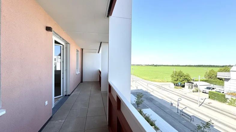 Langer Balkon mit Fliesenboden und weitem Blick über grüne Felder und die Landschaft.