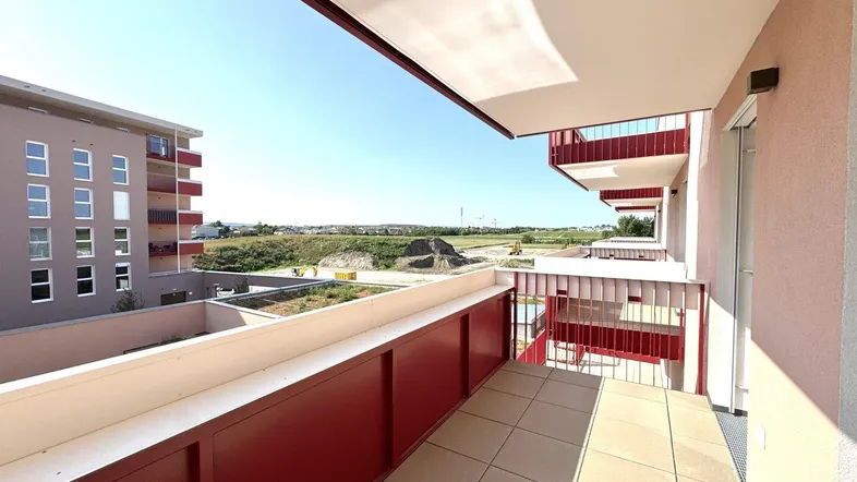 Geräumiger Balkon mit Fliesenboden und rotem Geländer, bietet Blick auf die umliegende Landschaft.
