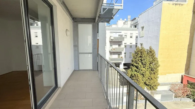 Langer Balkon mit Fliesenboden und Blick auf die umliegenden Gebäude.